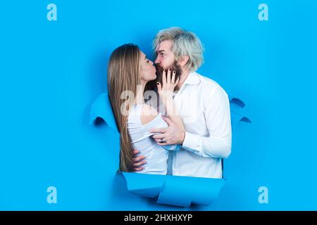 Couple in hole paper. Discount and sale. Kissed couple of bearded man and happy woman making hole in paper kiss through hole. Advertising board, blue Stock Photo