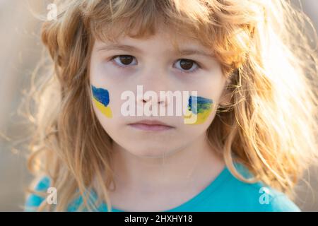 Ukraine flag on kids cheek. Little ukrainian patriot. Stock Photo