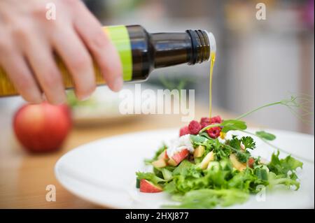 Adding some olive oil to the salad. Selective focus and shallow depth of field. Stock Photo