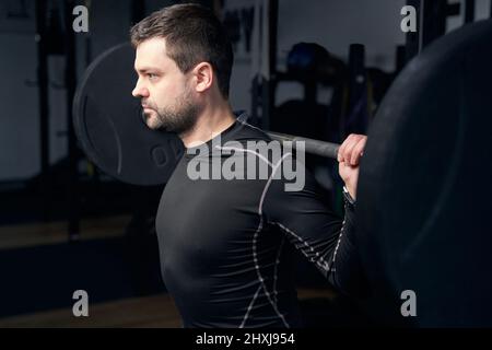 Athletic man doing exercise with barbell in gym Stock Photo