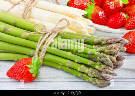 Fresh green and white asparagus with strawberries on wooden background closeup Stock Photo