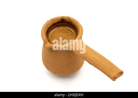 Turkish coffee in a clay pot isolated on a white background. Traditional Turkish cuisine flavor. close up Stock Photo