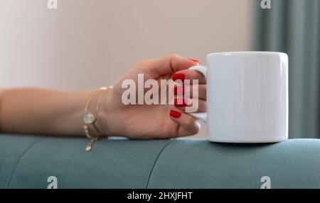 Cup. Mug Mockup. A single white sublimation printable mug and woman hand. Unbranded mug image available to all mug sellers and mug designer. Stock Photo