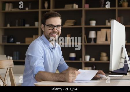 Business portrait smiling young manager sitting by computer at workplace Stock Photo