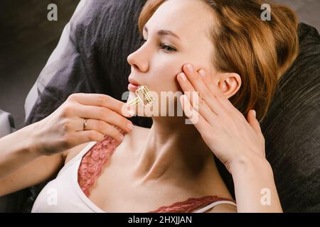 Focused woman massaging her face with a tipped gua sha roller Stock Photo