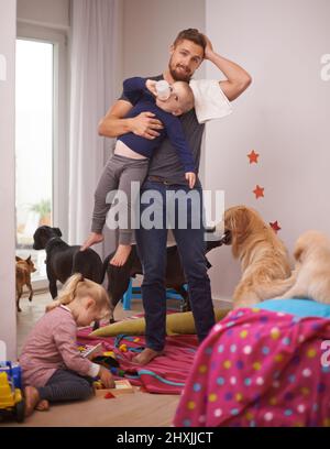 This is too much. An overwhelmed dad surrounded by his kids and dogs. Stock Photo