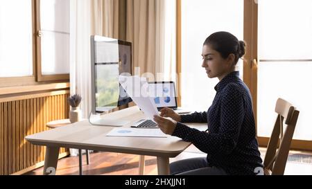 Young lady study data in report and on computer screens Stock Photo