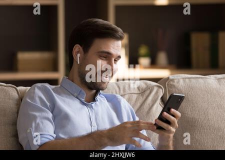 Smiling young man in headset make video call on smartphone Stock Photo
