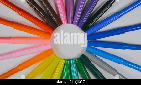 Many colored pencils are arranged around the edges of the image as a frame. In the center is an empty background with space for text. Mock up with copy space. Stock Photo