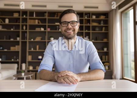 Webcam view male teacher sit at desk look at camera Stock Photo