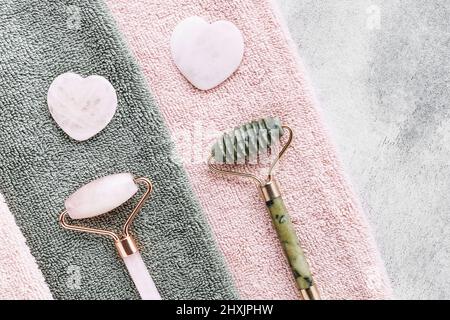 Face Massage tools. Gua Sha massages and jade facial rollers on a pink towel. SPA concept. Top view, copy space for text Stock Photo