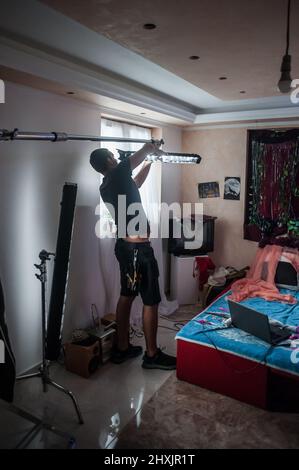 Behind the scene. Filmmaking lighting technician electric engineer adjusting and setup lights for movie film scene indoor. Light Department. Film Crew Stock Photo