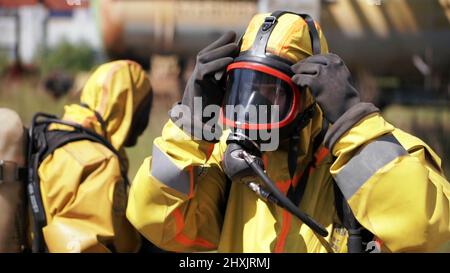 Man adjusting a gas mask. Clip. An employee who is wearing a gas mask and a yellow suit is an outdoor worker who is walking from behind