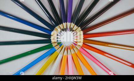 Many colored pencils are arranged around the edges of the image as a frame. In the center is an empty background with space for text. Mock up with copy space. Stock Photo