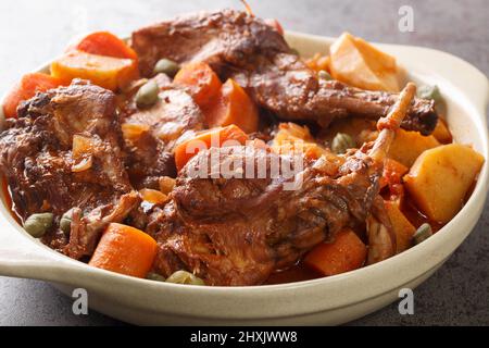 Rabbit stewed in red wine with vegetables and garlic close-up in a saucepan on the table. horizontal Stock Photo