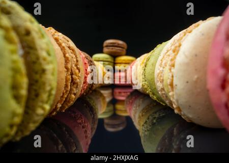 Colored macaroons confectionery marshmallows on a black reflective background in perspective. Extreme macro. Stock Photo