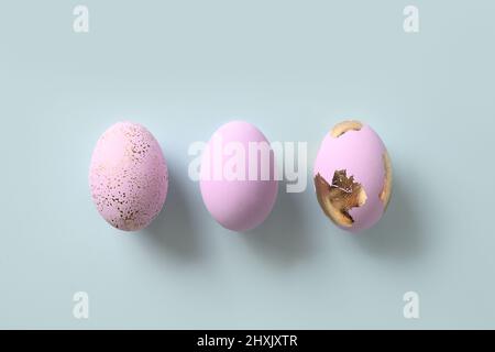 Three violet decorative pastel eggs on blue background. Flat lay. Happy Easter greeting card with copy space. Top view. Stock Photo