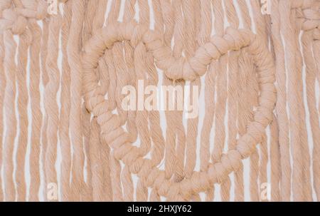 Wall panel in the style of Boho made of cotton threads in natural color using the macrame technique for home decor. close up Stock Photo