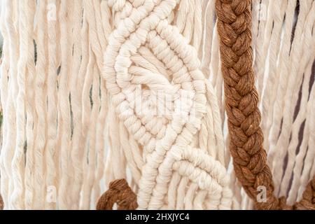 Wall panel in the style of Boho made of cotton threads in natural color using the macrame technique for home decor. close up Stock Photo