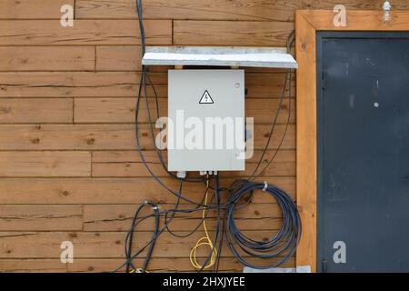 Electrical panel on a wooden wall with unprotected wires. Stock Photo