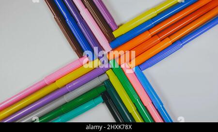 Many colored pencils are arranged around the edges of the image as a frame. In the center is an empty background with space for text. Mock up with copy space. Stock Photo