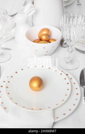 Beautiful table setting with golden Easter eggs in room, closeup Stock Photo