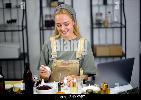 fragrance bottles used for blending scent for making perfume by professional female perfumer in cozy modern laboratory. smiling caucasian female in un Stock Photo