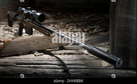 Bolt action rifle with scope and silencer in an abandoned building Stock Photo