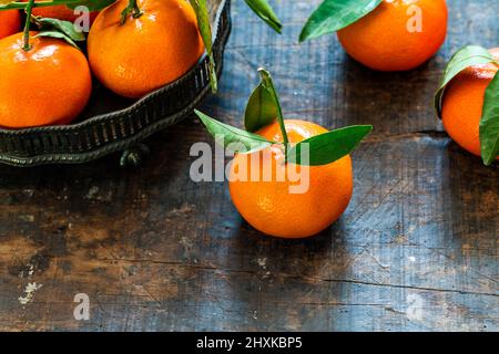 Mandarin oranges with green leaves on wooden table Stock Photo