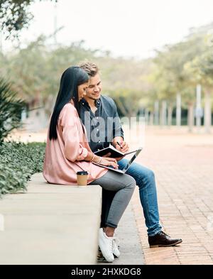 When the student is ready the master appears. Shot of two young students using a laptop while sitting outside on campus. Stock Photo