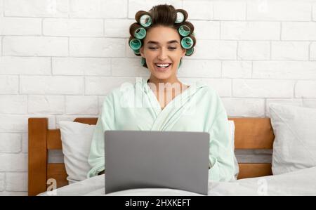 Happy Glamorous Lady Using Laptop Computer Working Online In Bedroom Stock Photo