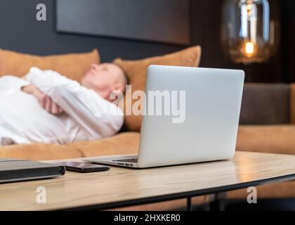 Exhausted tired businessman lying on sofa in office, relaxing after hard work day. Overtime work, overload and burnout concept. High quality photo Stock Photo