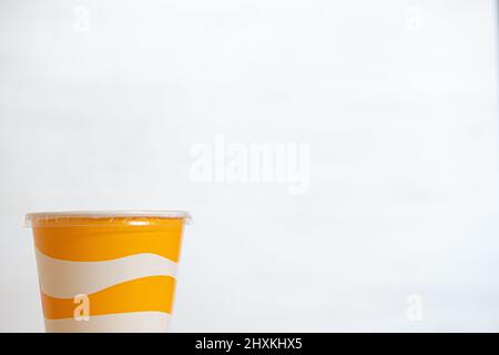 Yellow and white striped plastic cup for soft drinks with copy space Stock Photo