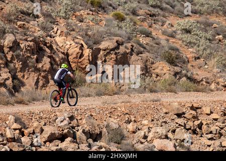 Cyclist riding a bike on a dirt trail in the mountains in Spain Stock Photo
