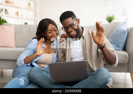Black couple having videocall using laptop waving hands Stock Photo