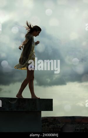 Living with abandon. Young woman walking on a rooftop with her arms outstretched. Stock Photo