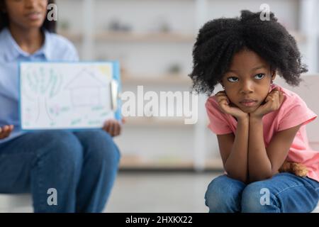 Bored little girl avoiding unrecognizable child psychologist Stock Photo