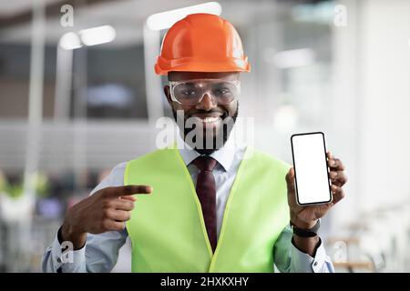 Happy african american architect pointing at smartphone with empty screen Stock Photo