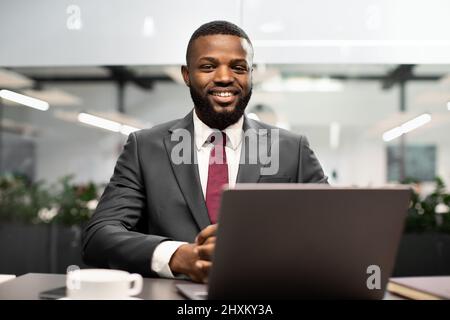 Handsome black businessman posing at workdesk in office Stock Photo