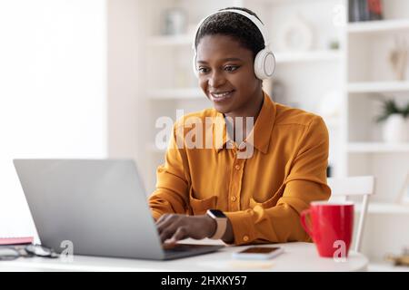 Attractive black woman attending webinar, using laptop and headset Stock Photo