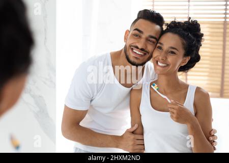 Happy Morning. Portrait Of Joyful Young Arab Couple Brushing Teeth In Bathroom Stock Photo