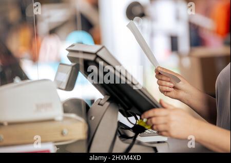 Young woman doing process payment with the bill or invoice on the POS cash terminal in the shop, finance concept Stock Photo