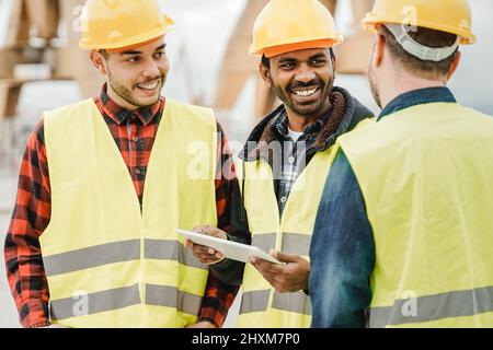 Multiracial engineer workers working at construction site using tablet computer - Focus on indian man face Stock Photo