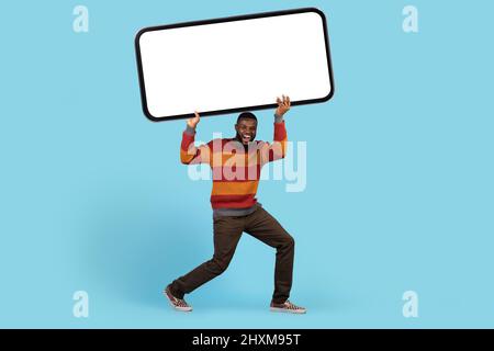 Crazy Offer. Funny African American Man Holding Big Blank Smartphone Above Head Stock Photo