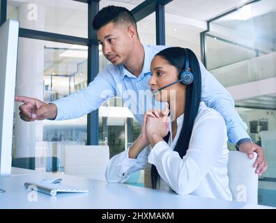 Take charge and make a change. Shot of a young man helping his colleague in a modern call centre. Stock Photo