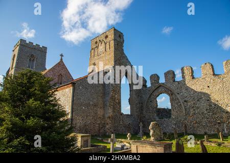 A side rear view of both the Church and Priory ruins of Weybourne Church in North Norfolk in the UK on a beautiful blue sky day Stock Photo