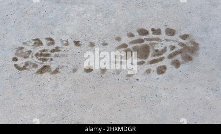 Human footprint on road surface. Foot steps leaving footprints. Stock Photo