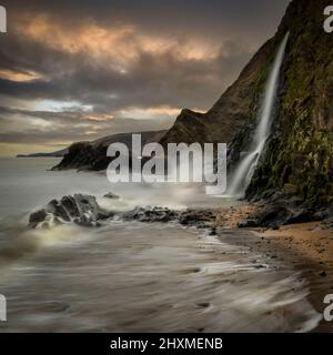 A long exposure of the sea and waterfall at Tresaith beach in West Wales UK Stock Photo