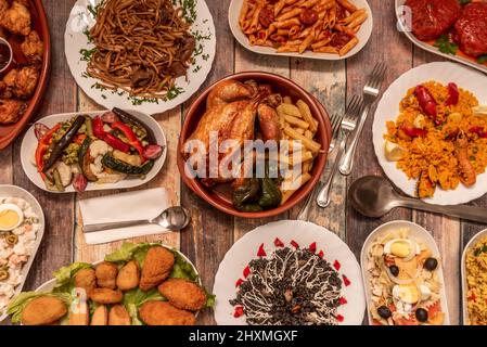 Set of assorted spanish food dishes and roasted chicken in clay pot with homemade french fries, fried green peppers. Paella plate with seafood, macaro Stock Photo