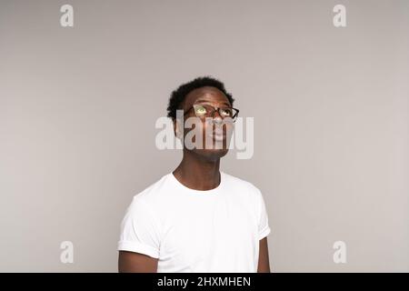 African American man in glasses wear white t-shirt thinking, looking up at copy space, isolated Stock Photo
